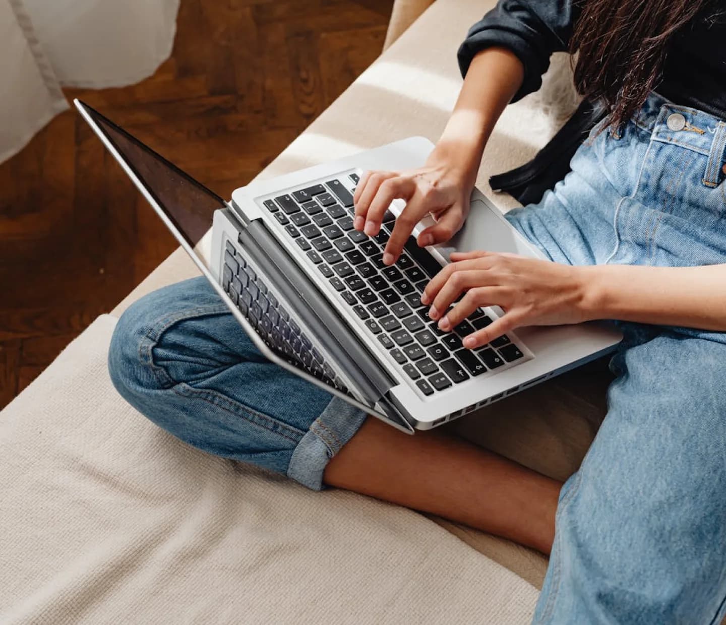 Eine Person, die einen Laptop benutzt und auf einem Sofa sitzt, stellvertretend für Website-Erstellung und Online-Arbeit